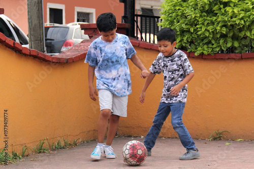 Ten-year-old Latino boys with dark skin play soccer in the street for fun and dream of becoming champions