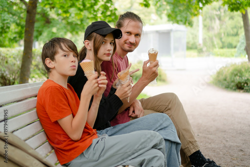 A child and a teenager in a happy family enjoying ice cream in the park. The image captures the essence of family bonding, laughter, and the joy of outdoor treats.