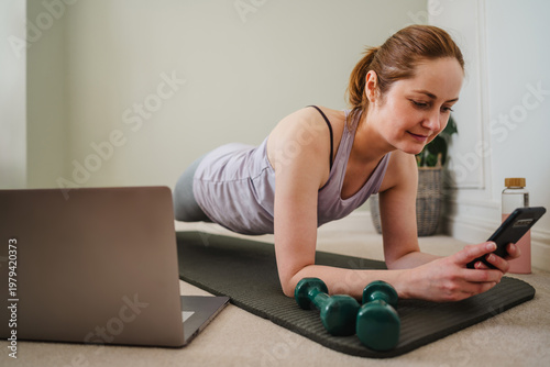 Woman exercising at home with virtual training on smartphone