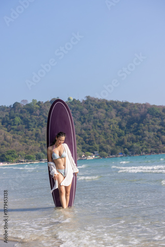 Photography Woman in a bright bikini surfing by the sea, enjoying fun and energetic ocean waves