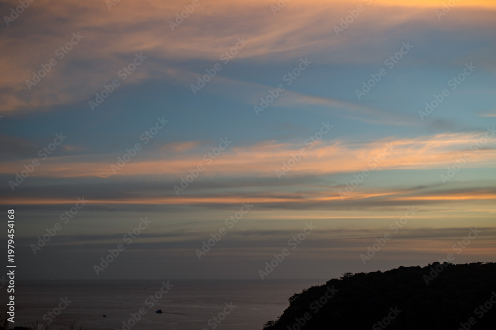 Obraz premium Colorful sunset sky with soft clouds over the Andaman Sea at Windmill Viewpoint Phuket, smooth horizon and tranquil water, relaxing evening atmosphere