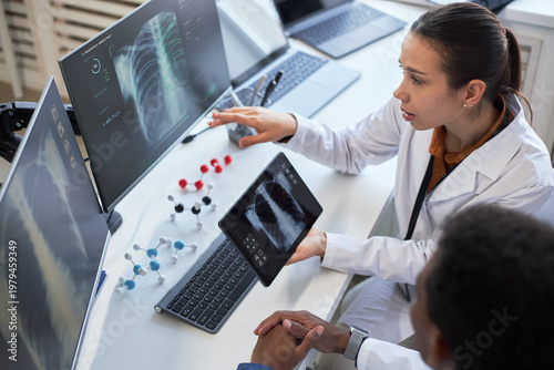 Fotografía Young adult Caucasian female doctor reviewing chest x rays on tablet and monitor while consulting colleague
