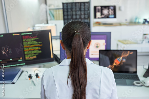 Fotografie Rear view of young adult woman scientist analyzing genetic data across multiple