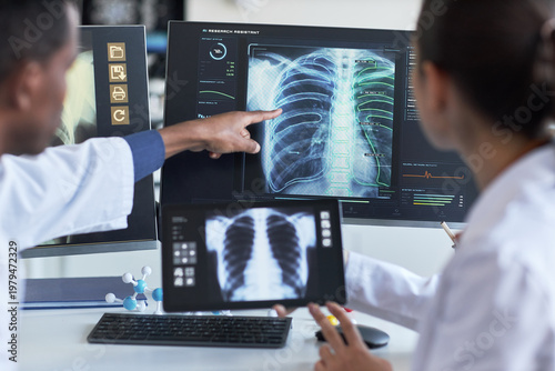 Bild auf Leinwand Doctors reviewing chest X ray scans on monitor and tablet, pointing at lung analysis for diagnosis and collaboration