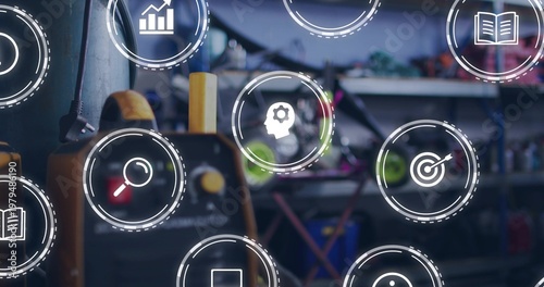 Displaying yellow-and-black battery charger with knobs and cables in workshop, with UI icons