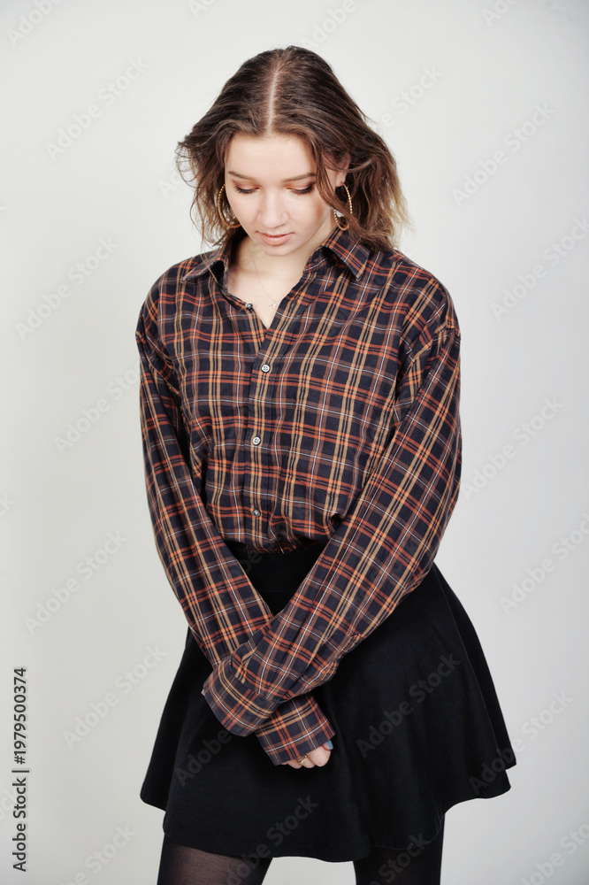 Fototapeta premium Blondes Model im Outfit mit Rock und Strumpfhose, nachdenkliche Pose, modernes Fashion- und Lifestyle-Porträt im Studio isoliert