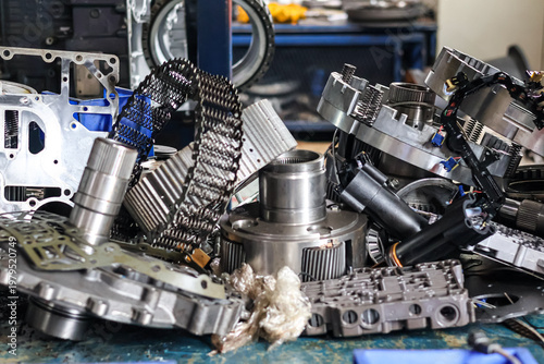 Quadro su tela High angle view of disassembled automatic transmission parts including planetary gears, valve body, and metal chains on a workbench in a car repair shop