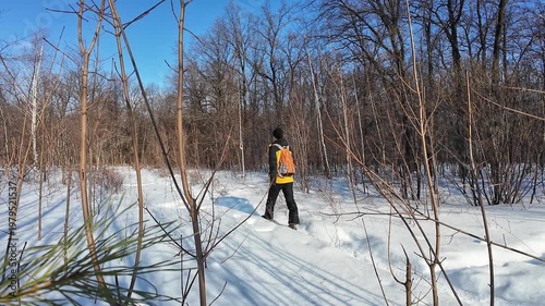 Hiker In Snow. Adventurer Dressed Brightly Navigates Snowy Thicket Terrain Energetically. Industrious Outdoors Person In Orange Coat Traversing Snowcovered Branches And Footprints Energetically