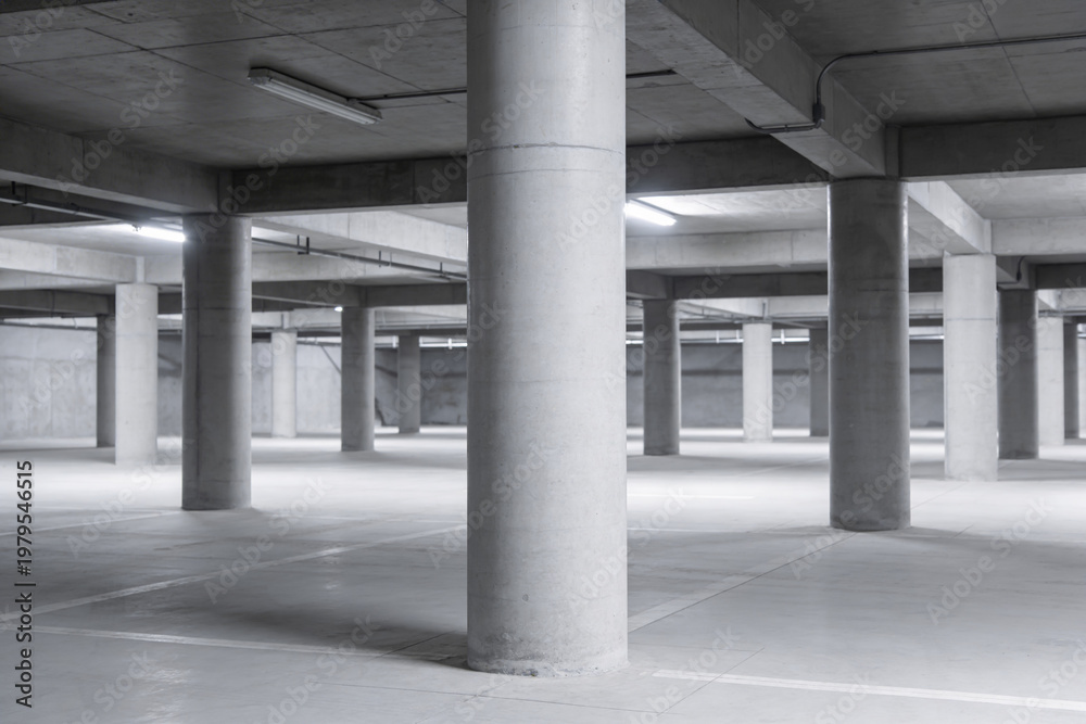 Fototapeta premium Vast concrete parking garage interior with rows of columns and overhead lighting