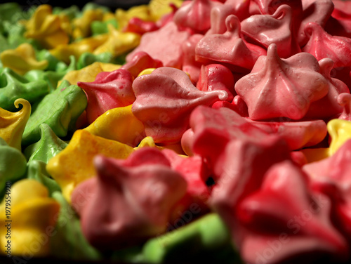 Colorful meringue shapes arranged on a tray during a baking event in a kitchen setting in the afternoon