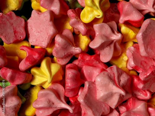 Colorful meringues in various shapes and sizes fill the table during a baking event in the kitchen