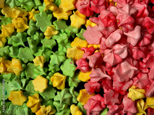 Colorful meringue shapes arranged in patterns on a table during a dessert display at a spring festival in a community center