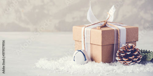 Christmas gift box in the snow on gray background. Christmas decor, winter mood, holiday decoration.