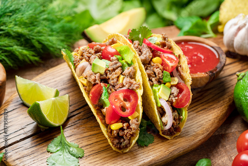 Tableau sur toile Mexican meat tacos or beef stuffed tortillas and lime slices near them on wooden serving board