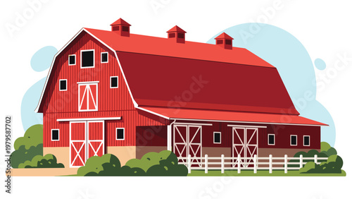 Classic large red wooden barn building located on a peaceful farm surrounded by green bushes and set against a clear blue sky background.