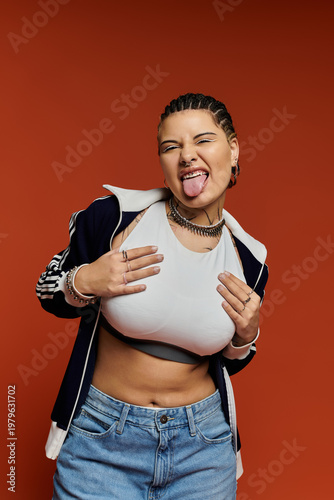 Stylish young woman posing confidently against a vibrant orange backdrop
