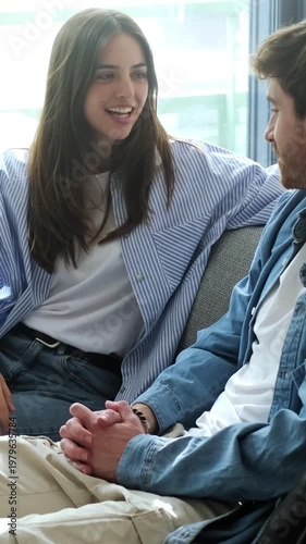 Happy Young Couple Holding Hands, Sharing a Loving Conversation on Their Sofa at Home