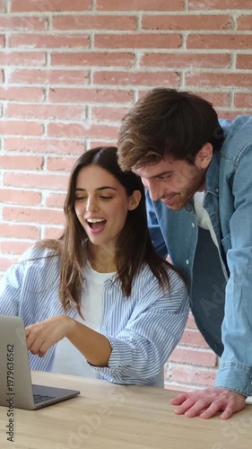 Happy Couple Laughing and Collaborating While Working on Laptop Together in a Casual Home Office.