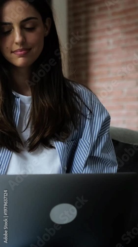 Focused Young Woman Works Thoughtfully on Her Laptop in a Cozy Home Office Setting