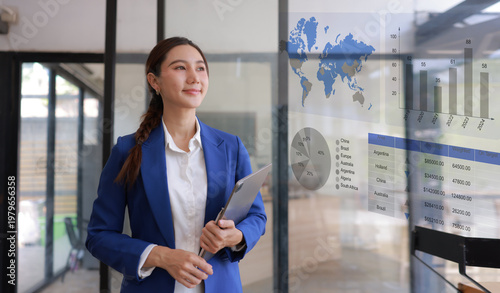 Professional Asian businesswoman using digital tablet to analyzing sales growth and financial data dashboard on virtual screen in modern office.