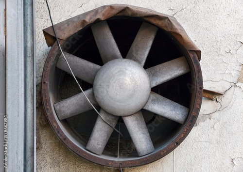 An old rusty industrial fan in the wall