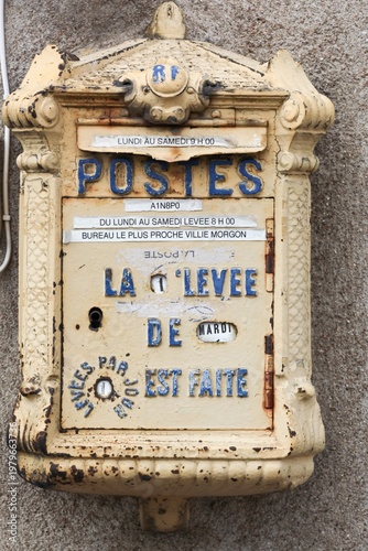 Old and vintage yellow French letterbox on a wall in Beaujolais, France