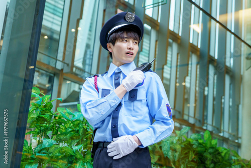 トランシーバーで会話する若い日本人男性警備員　撮影協力：学校法人電波学園　東京電子専門学校