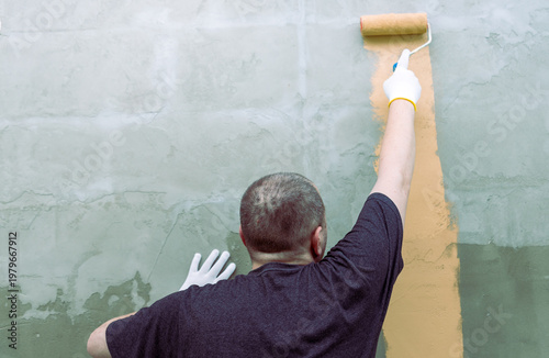 Wallpaper Mural Worker applies fresh paint to concrete wall with roller Torontodigital.ca
