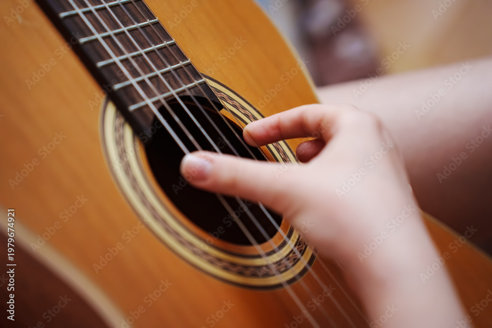 Fototapeta premium Playing guitar in a cozy indoor space during the afternoon