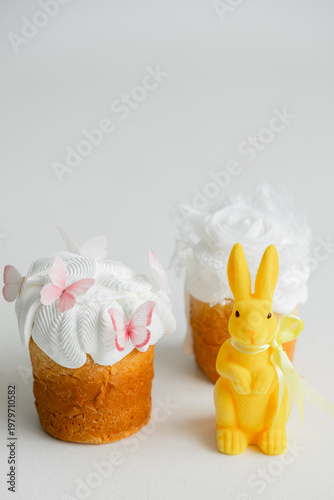 Easter composition with traditional cakes and yellow bunny on light background, festive spring concept with copy space and soft minimal aesthetic.