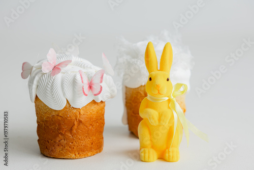 Easter composition with traditional cakes and yellow bunny on light background, festive spring concept with copy space and soft minimal aesthetic.