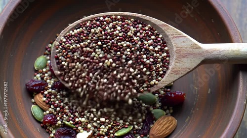 Quinoa Seeds Pouring from a Wooden Spoon into a Rustic Brown Bowl
