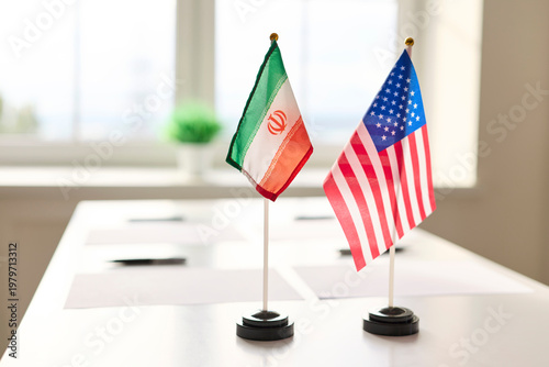 Flags diplomacy meeting on table symbolize negotiations. Iran and United States flags at conference table; dialogue, agreement, conflict. Represents international relations and strategic negotiation.