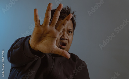 Foto An alarmed adult male wearing a dark casual jacket holds his hand out flat toward the viewer in a clear stop gesture with his mouth open in sudden shock or warning