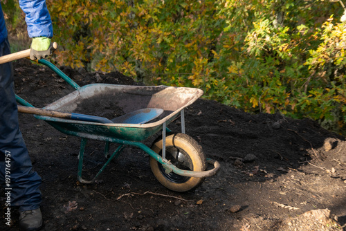Green Wheelbarrow on a Dirt Pile The Concept of Gardening Activity.