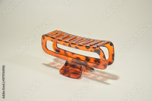 Amber tortoise shell hair claw clip isolated on plain background. Stylish plastic hair clamp for women fashion accessories, beauty styling, and daily grooming.