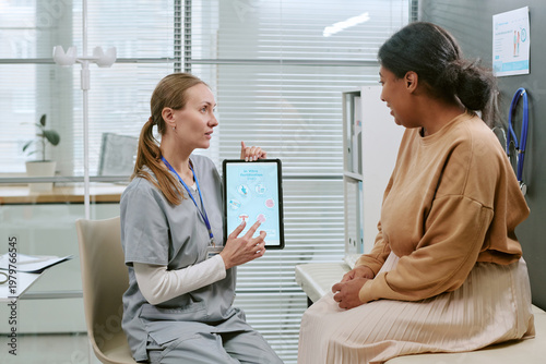 Bild auf Leinwand Caucasian female doctor showing tablet and explaining IVF treatment to Black wom