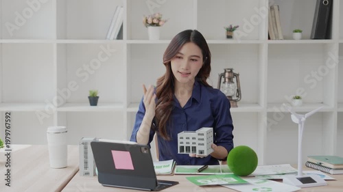 An Asian woman uses a laptop to present topics on ESG (Environmental, Social, and Governance) on a screen, including sustainable business practices and working from home concepts.