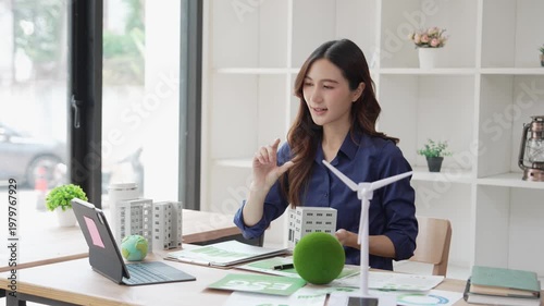 An Asian woman uses a laptop to present topics on ESG (Environmental, Social, and Governance) on a screen, including sustainable business practices and working from home concepts.