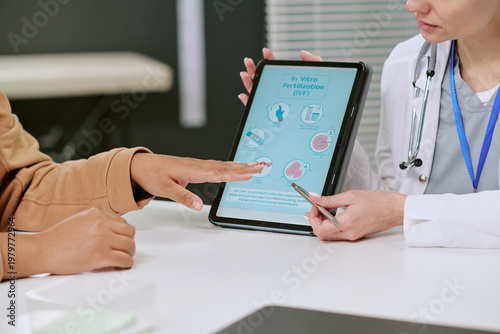 Photos Close up of female doctor showing IVF treatment process on tablet, guiding woman