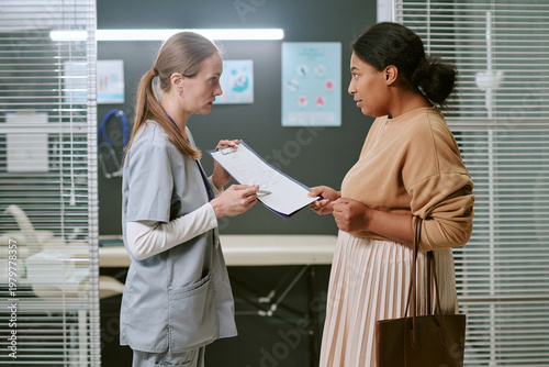 Tableau sur toile Medium shot of Caucasian female doctor consulting pregnant woman, reviewing medi