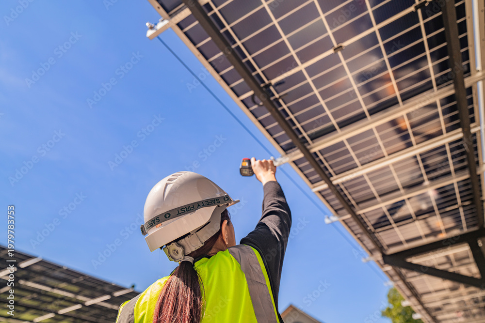 Fototapeta premium Engineer inspecting solar panels under a solar-powered carport on a sunny day, ensuring optimal performance. Focus on renewable energy, sustainability, green power, and eco-friendly solar solutions.