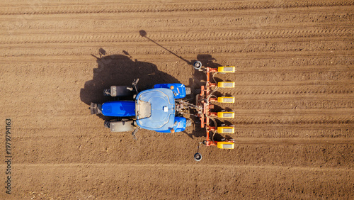 Aerial view of a bright blue tractor with orange implements contrasts against the rich brown earth of a freshly plowed field, Sremska Mitrovica, Vojvodina, Serbia.