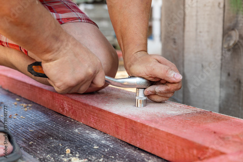 Foto Ratchet socket wrench is used to tighten bolt during outdoor assembly by outdoor