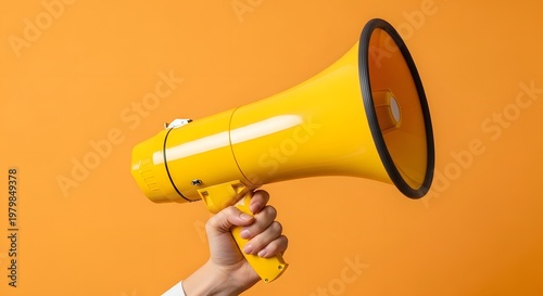 Hand Holding a Yellow Megaphone on Solid Orange Background - Communication, Marketing, and Announcement Concept