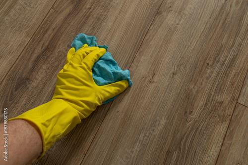 Photos Dusting and mopping the floor in yellow rubber gloves, cleaning before the holid
