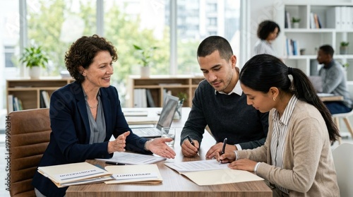 Three professionals are seated around a wooden table, reviewing documents and signing a contract.