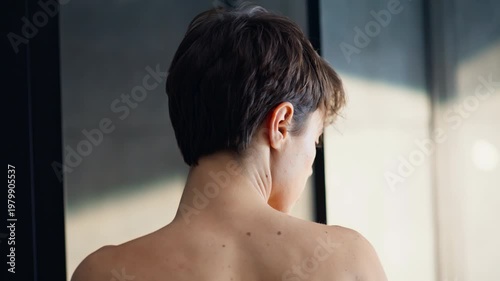 Short haired brunette removing robe closeup. Bare shoulders woman spa session