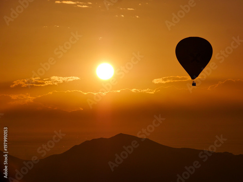 Silhouette of hot air balloon against dramatic sunset with sun at horizon near Marrakesh Morocco