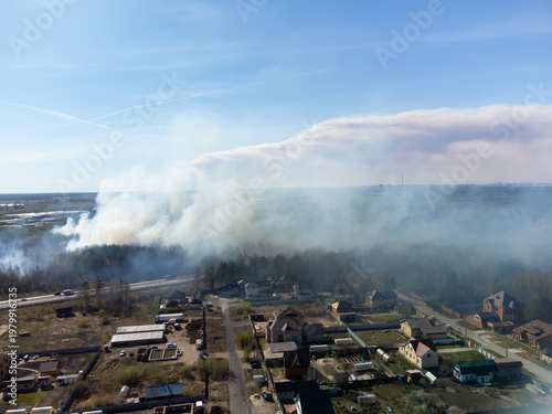 High-angle drone shot (top-down / bird's-eye view) of a forest fire (wildfire / bushfire) burning near suburban residential areas, captured using a DJI Mini 2. The image shows a massive plume of thick